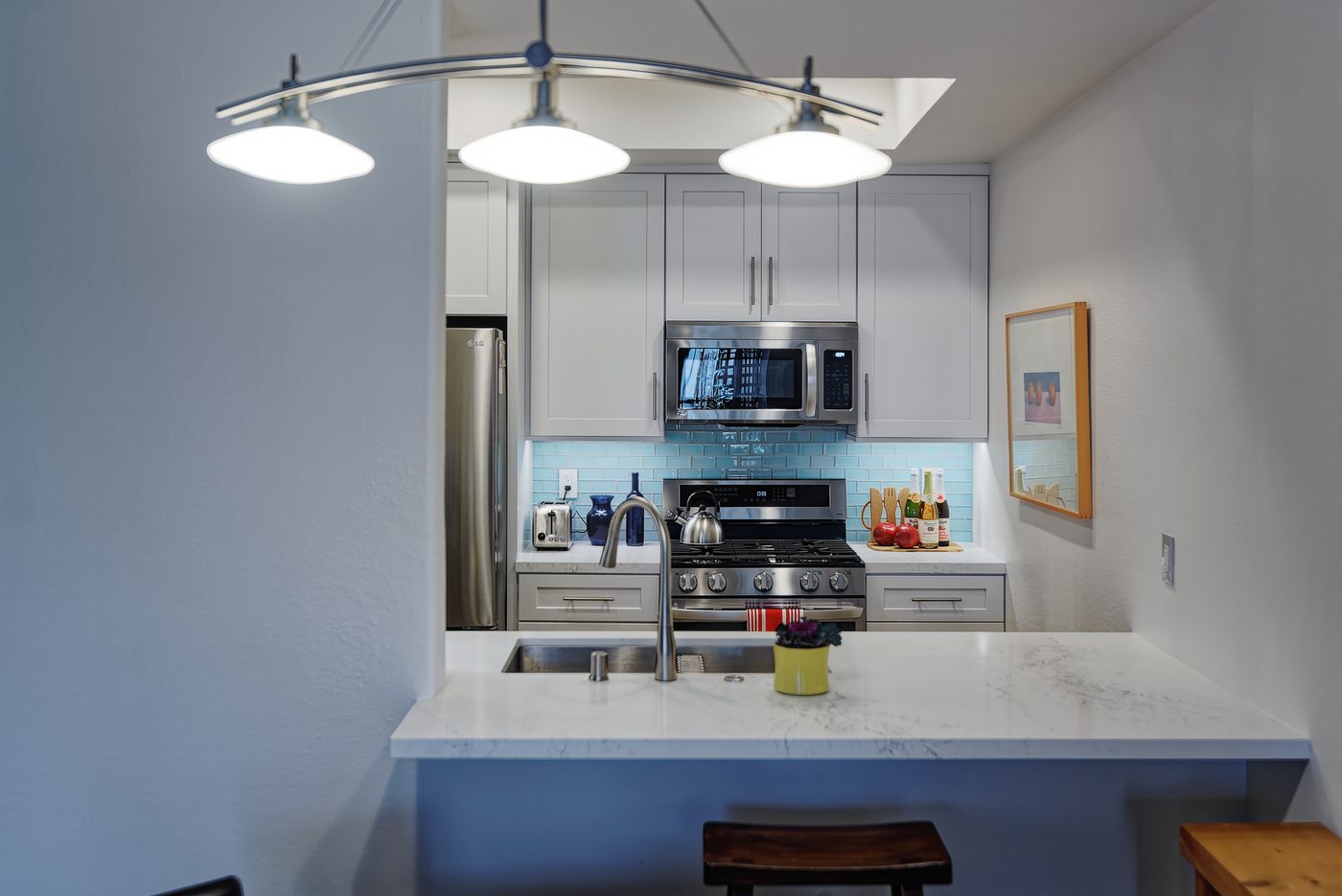 White shaker kitchen with blue subway tile backsplash and marble peninsula in Los Angeles