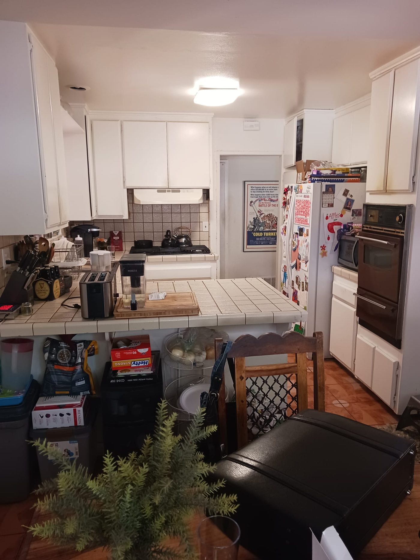 Before: cluttered white kitchen with tile counter in Sherman Oaks