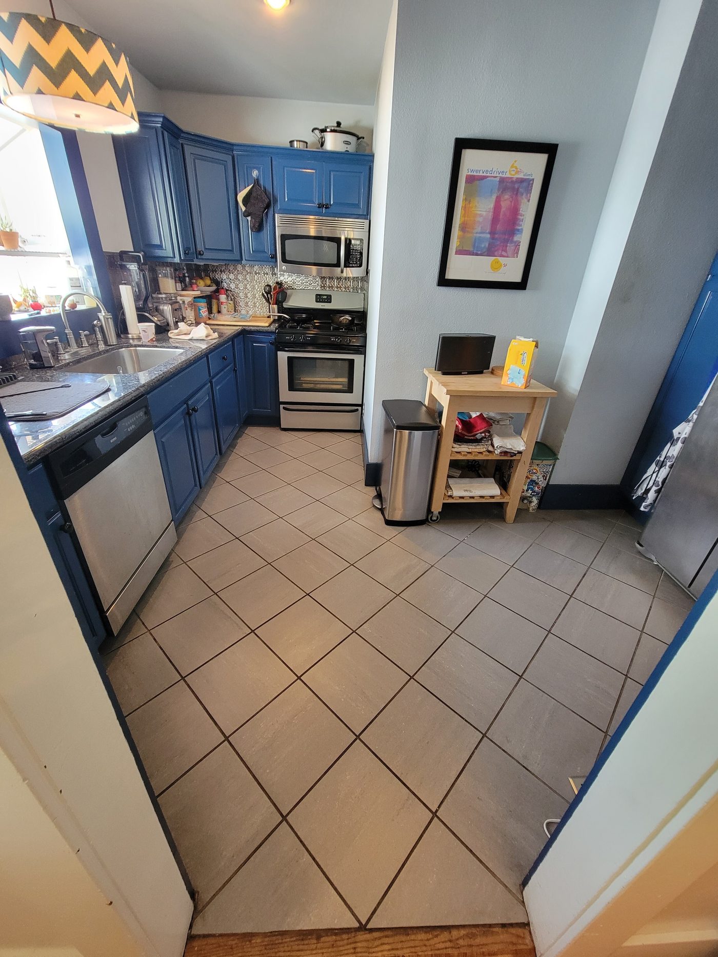 Before: dated blue cabinet galley kitchen with tile floor in Los Feliz