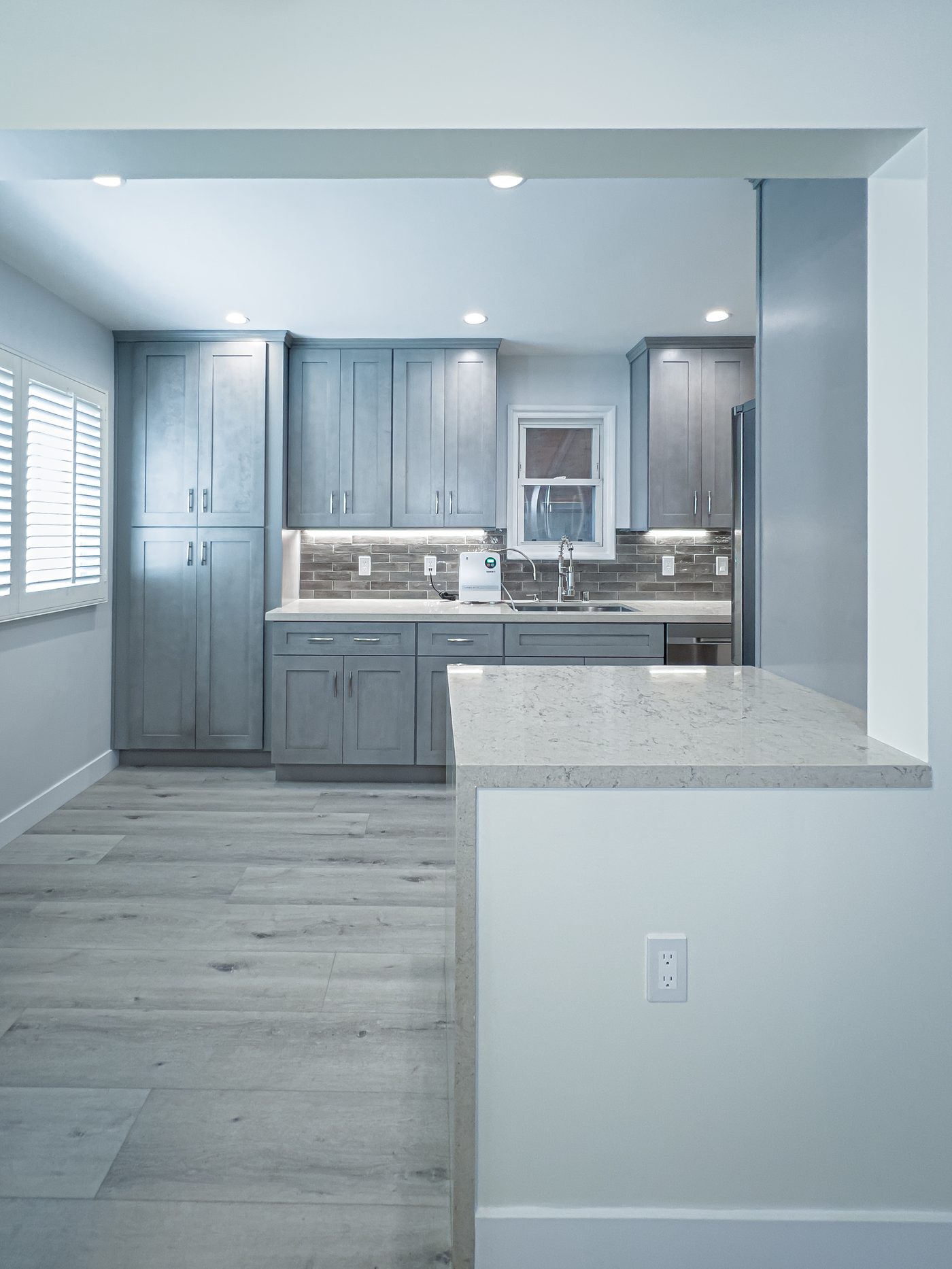 Gray transitional kitchen with marble peninsula and wood floors in Long Beach