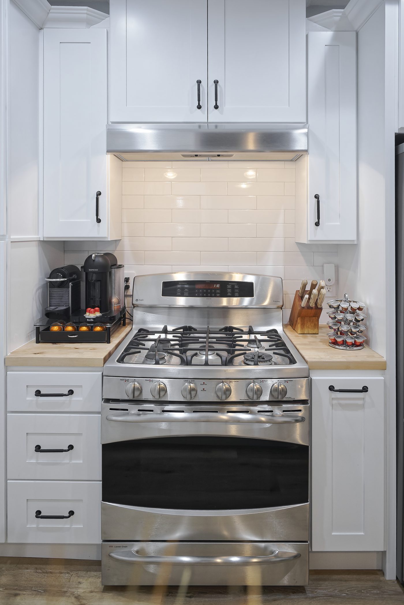 Compact white shaker kitchen with butcher block counters and gas range in Studio City
