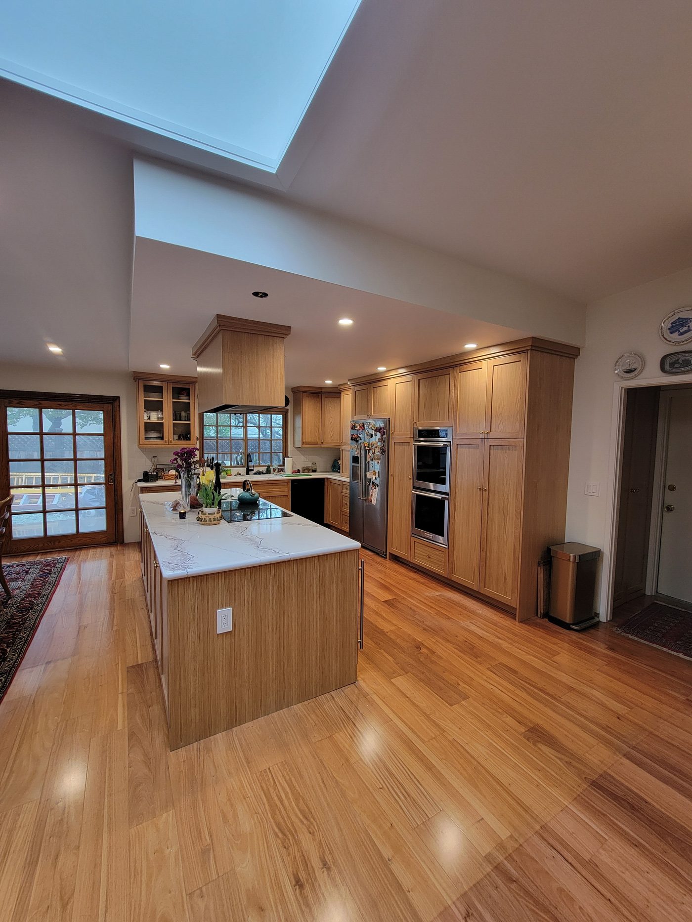 Open space custom natural wood kitchen with large island, skylight, and hardwood floors in Rancho Palos Verdes