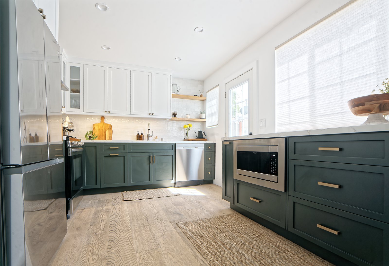 Two-tone modern custom kitchen with dark green cabinets, white uppers, and marble counters in Los Angeles