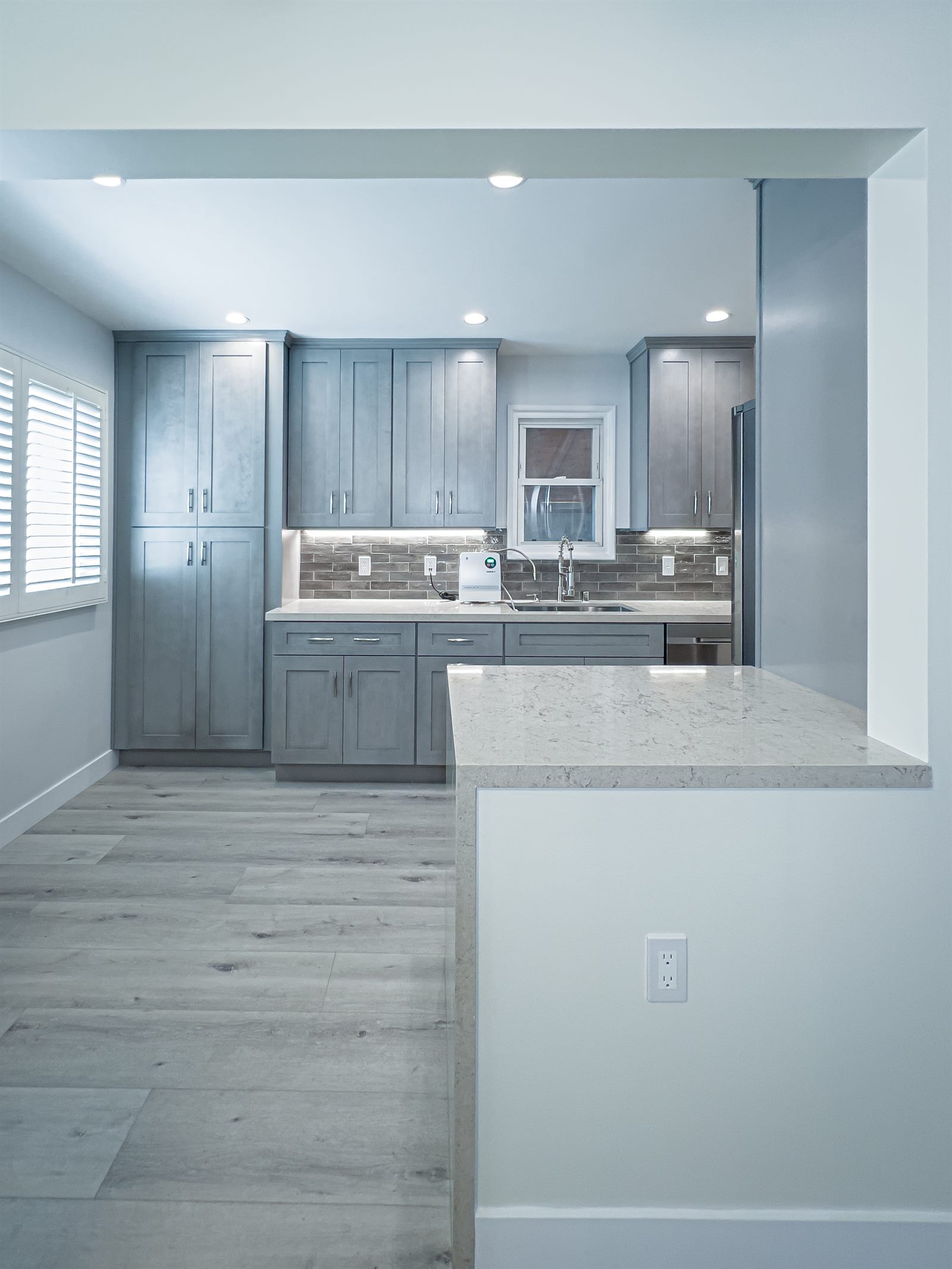 After: gray transitional kitchen with marble peninsula and sink view