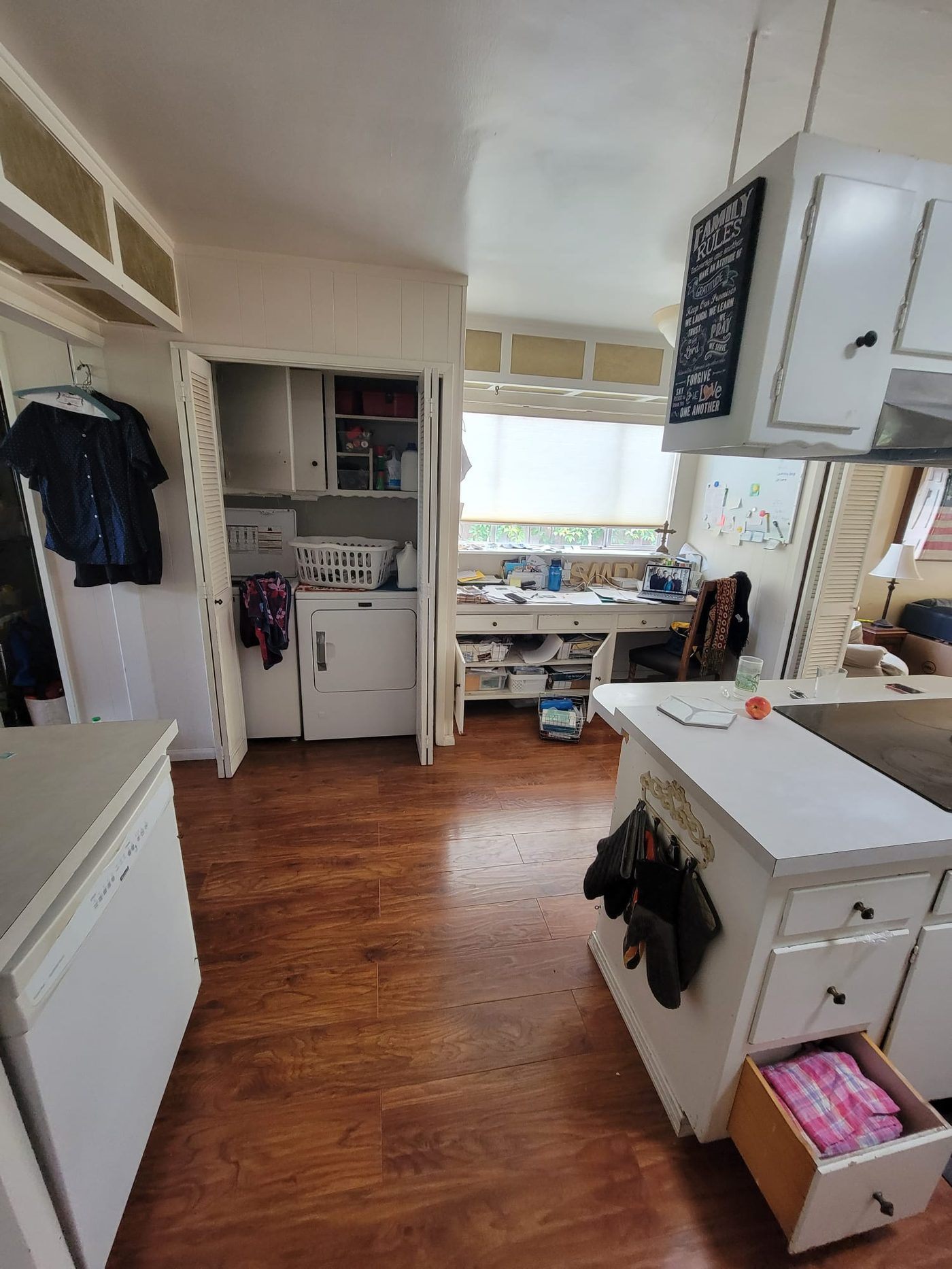 Before: Proft kitchen side view showing laundry alcove and white cabinets