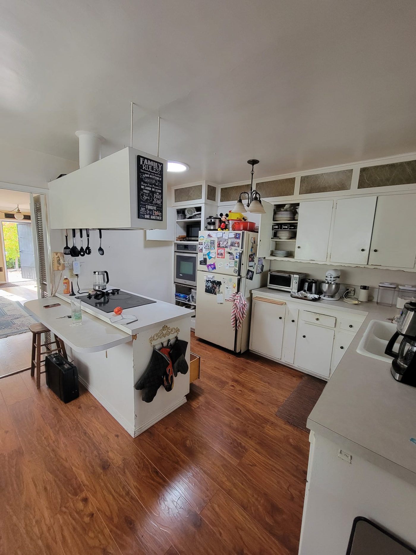 Before: original Proft kitchen with white cabinets, dated lighting, and white peninsula