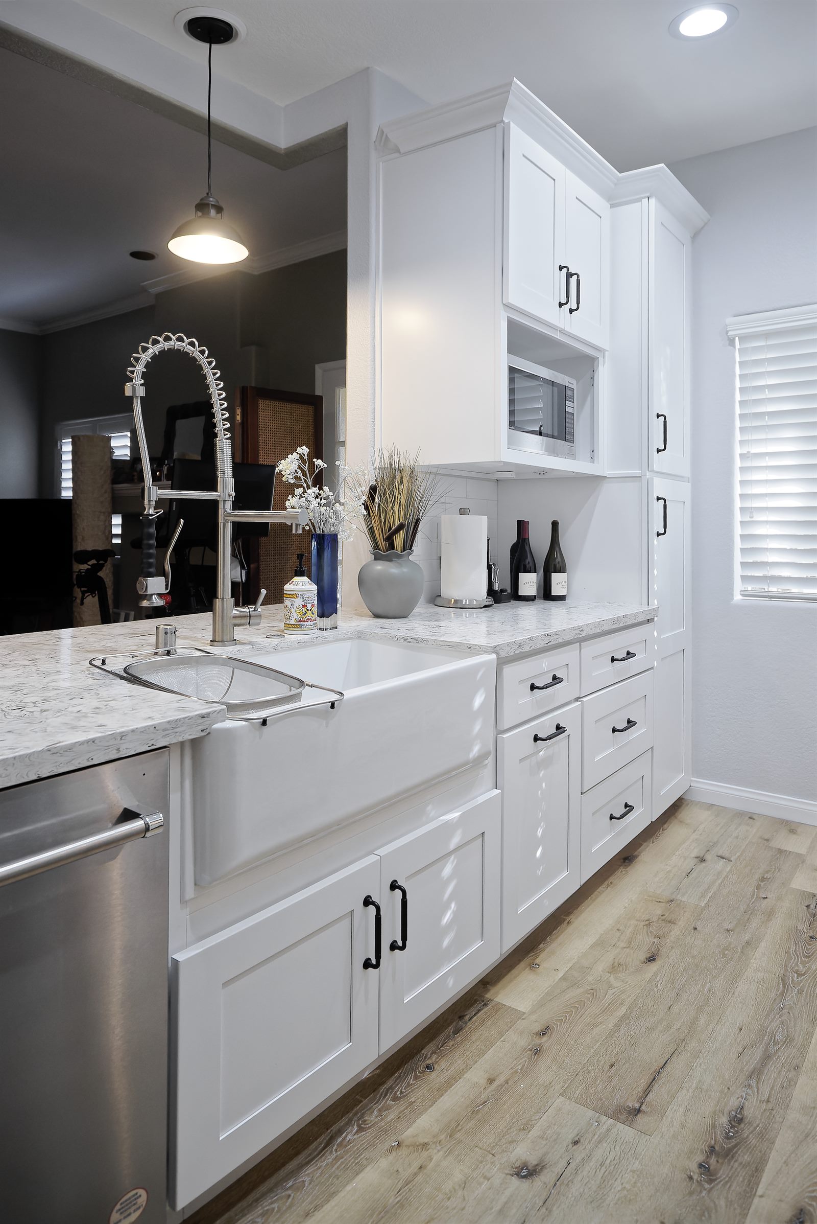 After: white shaker kitchen sink view with new cabinetry and flooring